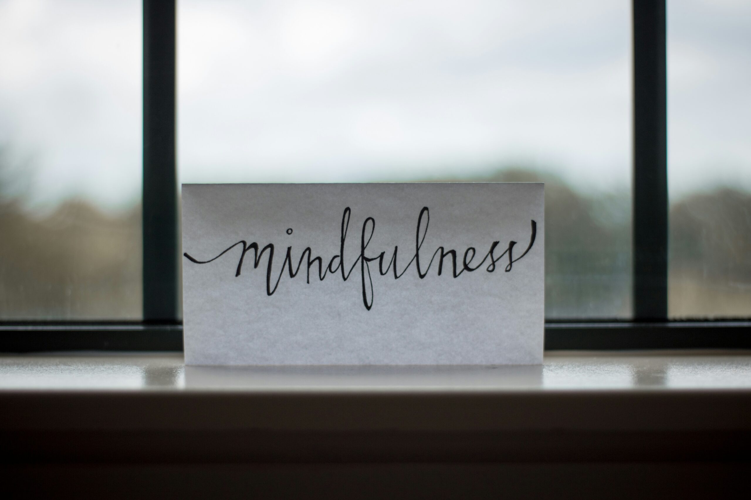 Academic leader practicing mindful stress reduction by the window, taking a conscious breath after work